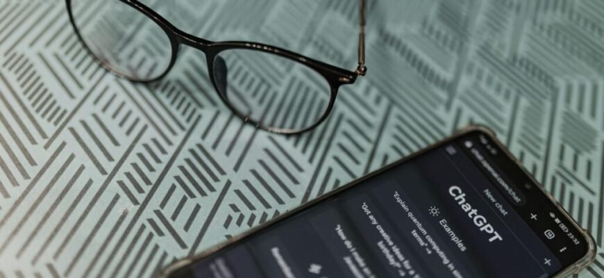 A smart phone with glasses on it next to a book