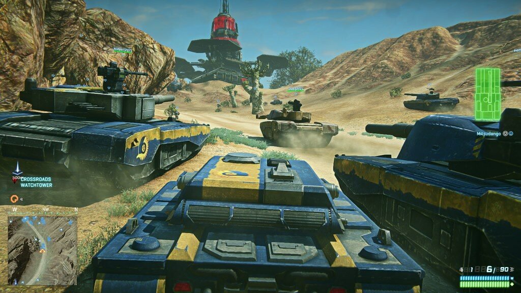 PLANETSIDE 2 | ILikeGuru Tanks in a desert battlefield advancing toward a central red beacon, dust clouds rising around them.